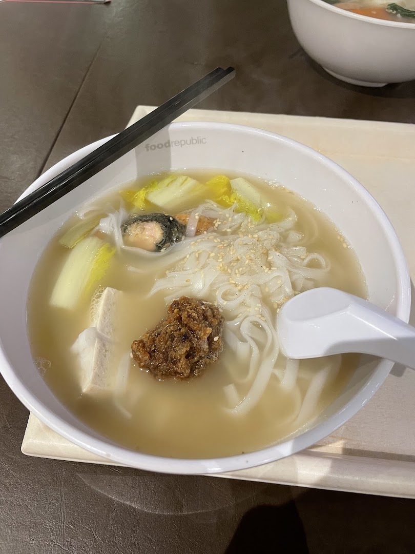 A close-up of a steaming bowl of Yong Tau Foo with flat noodles, vegetables, and various ingredients.