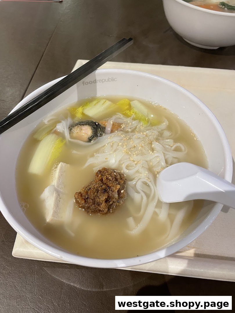A close-up of a steaming bowl of Yong Tau Foo with flat noodles, vegetables, and various ingredients.