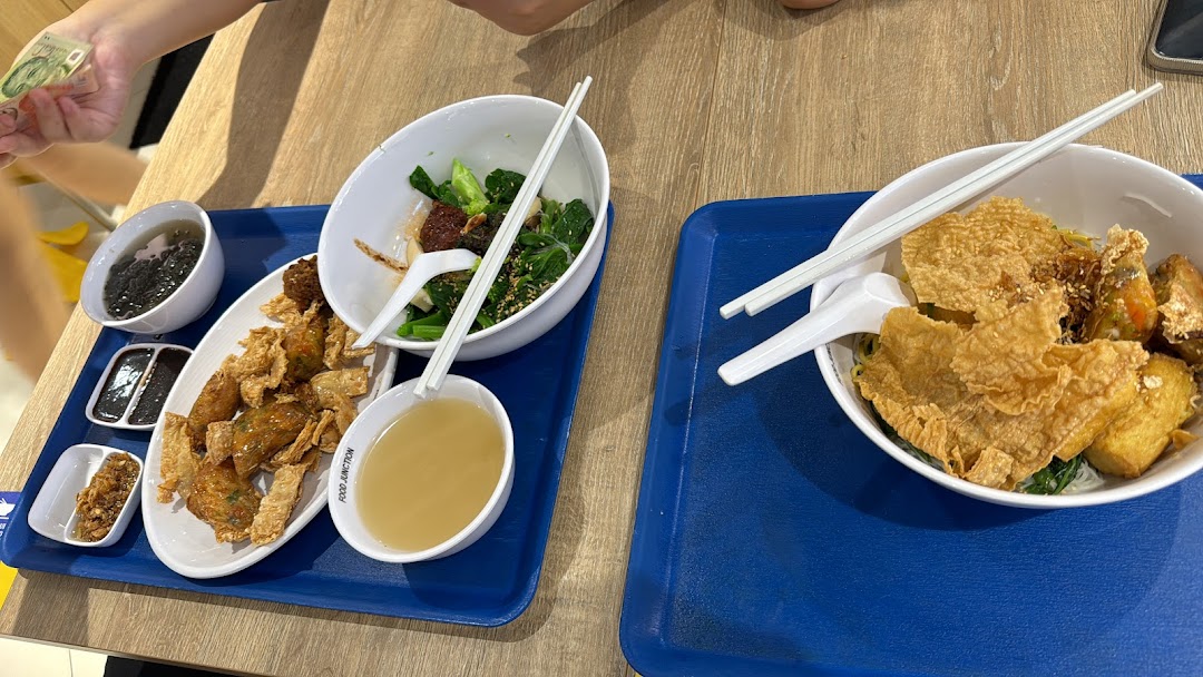 Two trays of delicious Yong Tau Foo dishes with various ingredients and sides on a wooden table.
