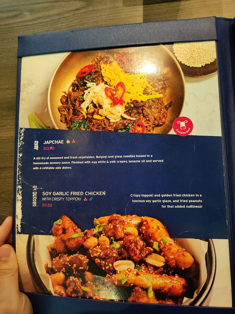 A menu page from Ajummas Westgate showcasing popular Korean dishes like Japchae and Soy Garlic Fried Chicken.