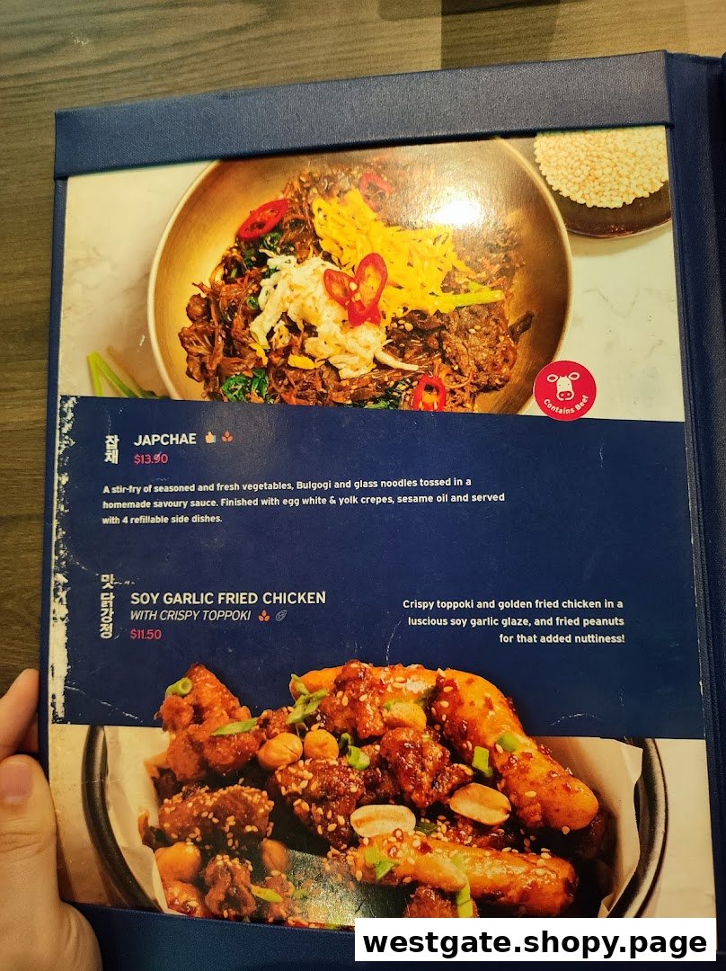 A menu page from Ajummas Westgate showcasing popular Korean dishes like Japchae and Soy Garlic Fried Chicken.