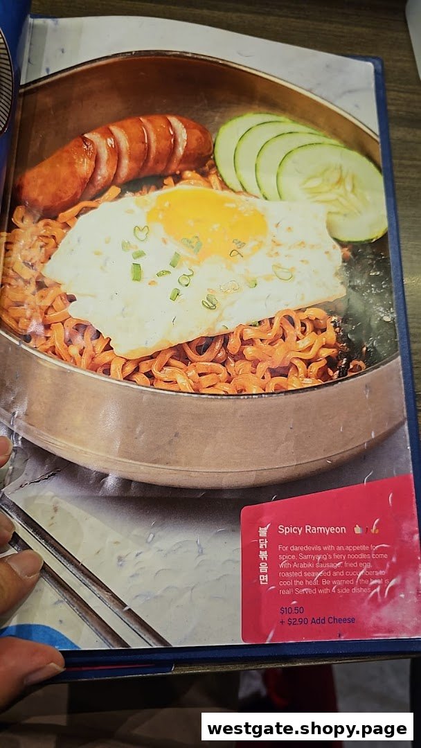 A menu page displaying a vibrant Spicy Ramyeon dish with sausage, egg, and cucumber.