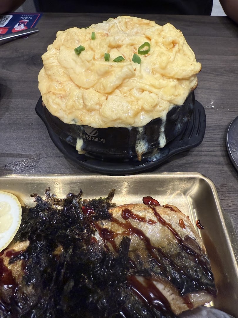 Close-up of delicious Korean dishes, including fluffy steamed egg and grilled fish with seaweed.