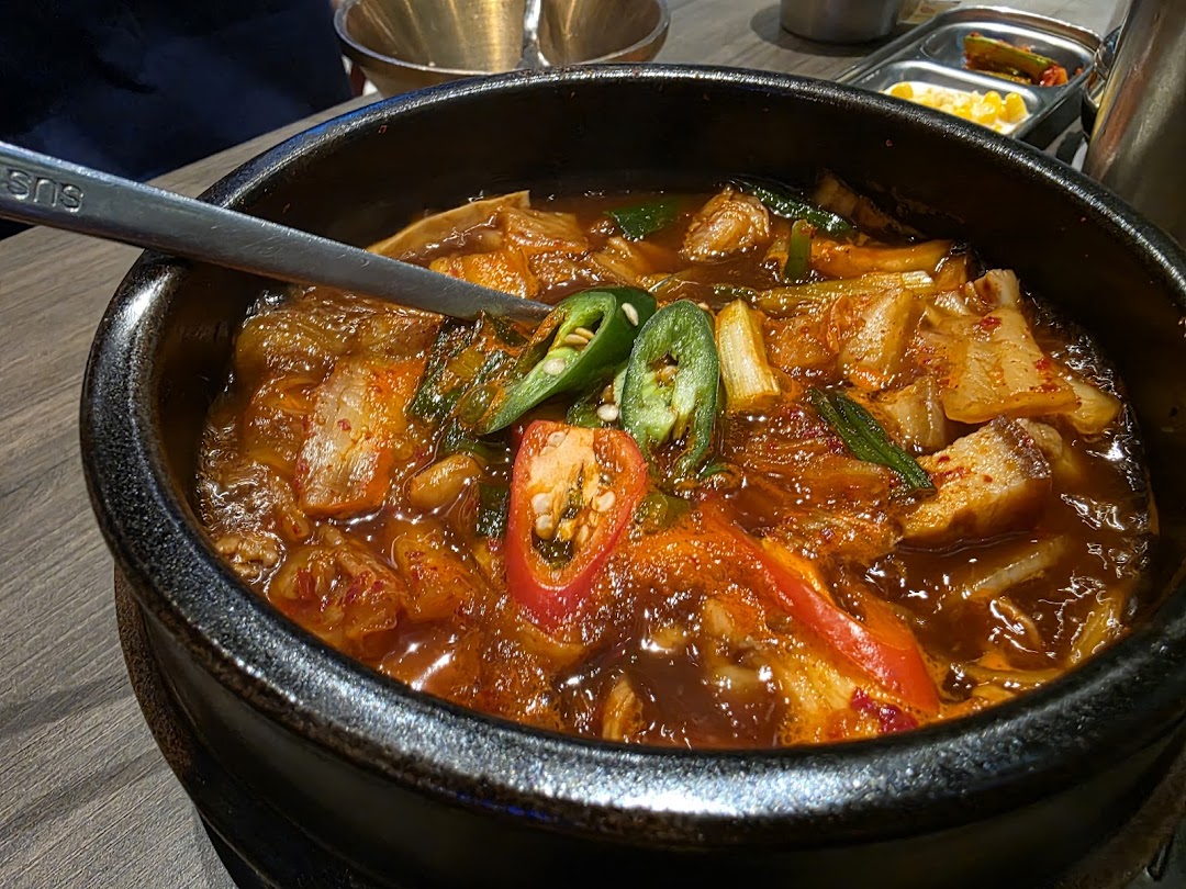 A close-up of a bubbling Korean kimchi stew (Kimchi Jjigae) served in a traditional stone pot.