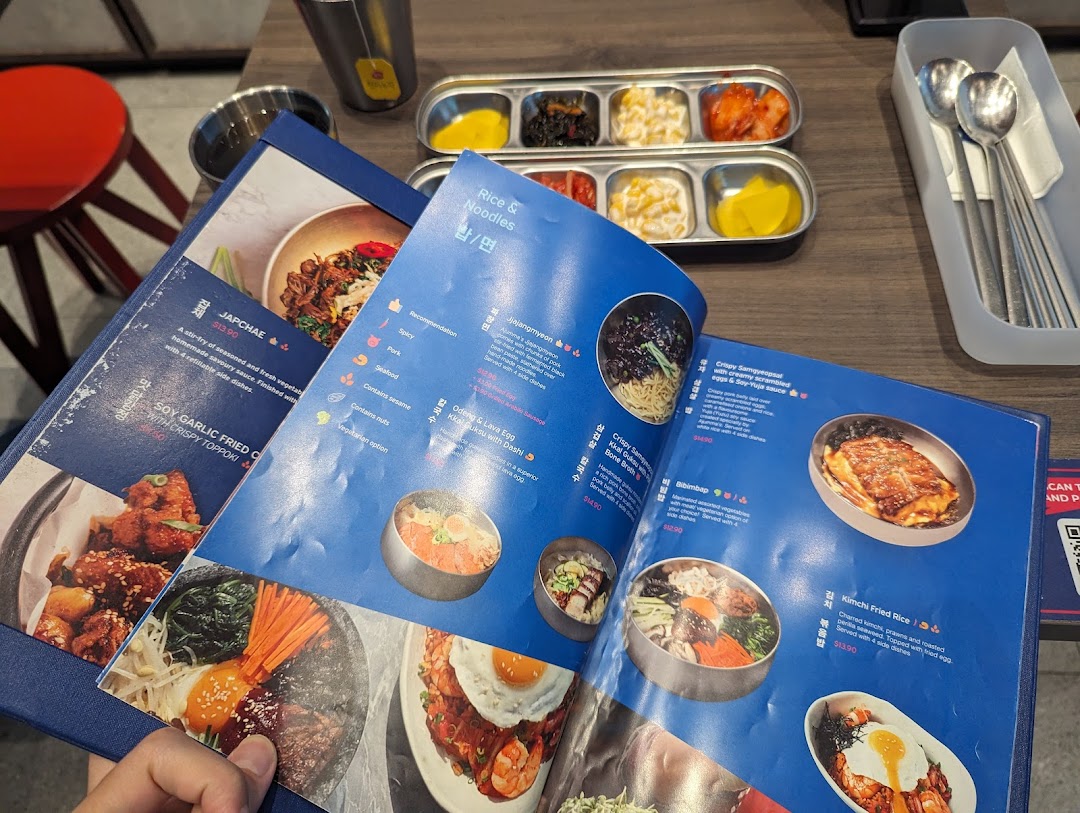 A close-up view of an open Korean restaurant menu displaying various dishes and prices.