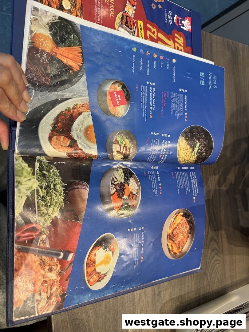 An open menu from Ajummas showcasing Korean rice and noodle dishes with prices and descriptions.