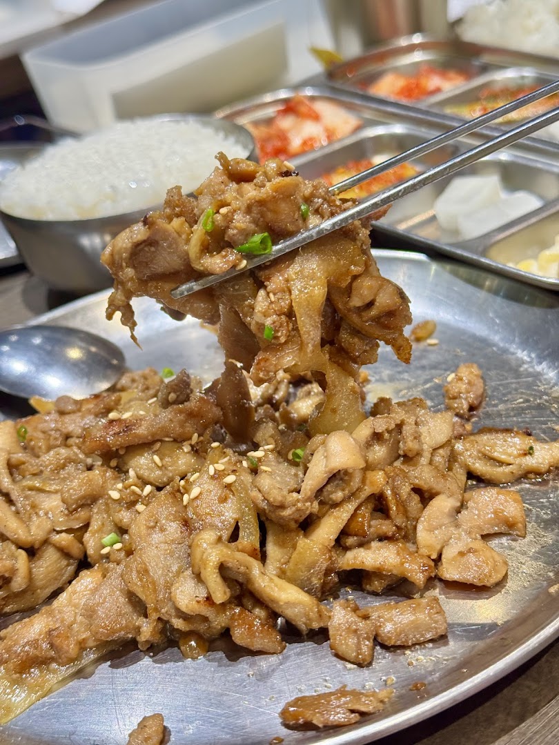 A close-up of delicious Korean stir-fried meat with rice and banchan, ready to be enjoyed.