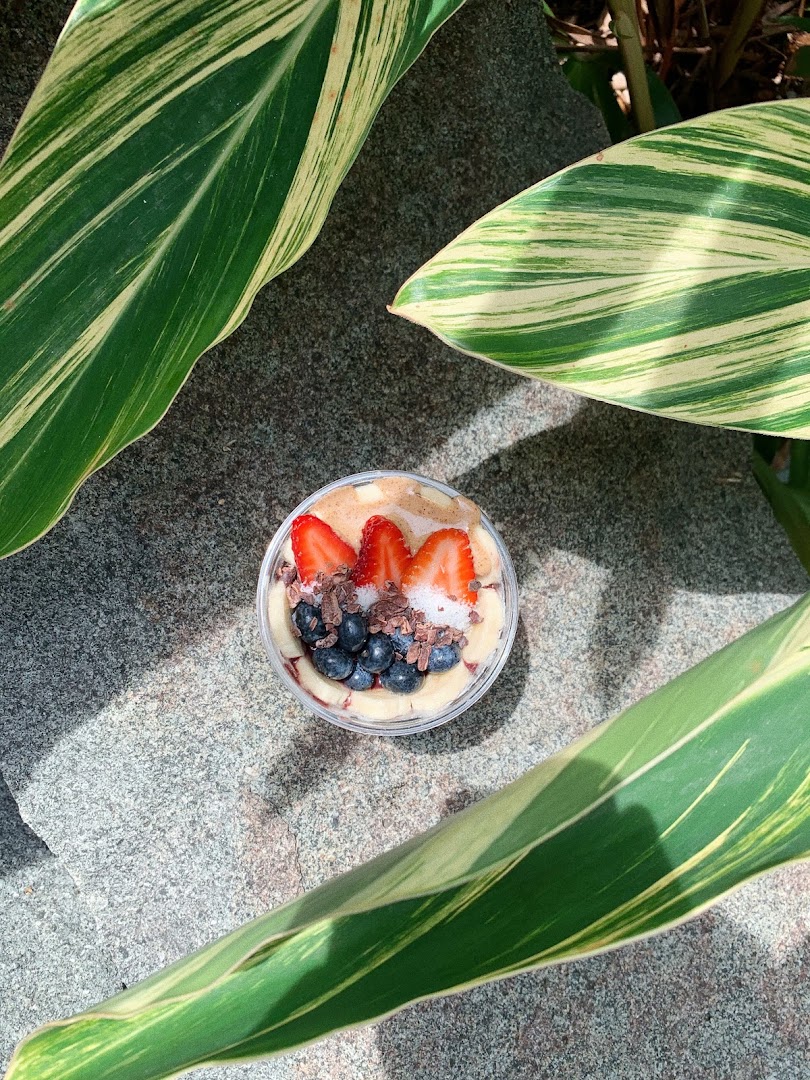 A vibrant açaí bowl topped with fresh strawberries, blueberries, and cacao nibs, set outdoors.
