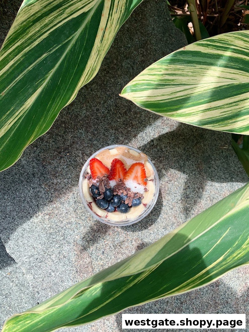 A vibrant açaí bowl topped with fresh strawberries, blueberries, and cacao nibs, set outdoors.