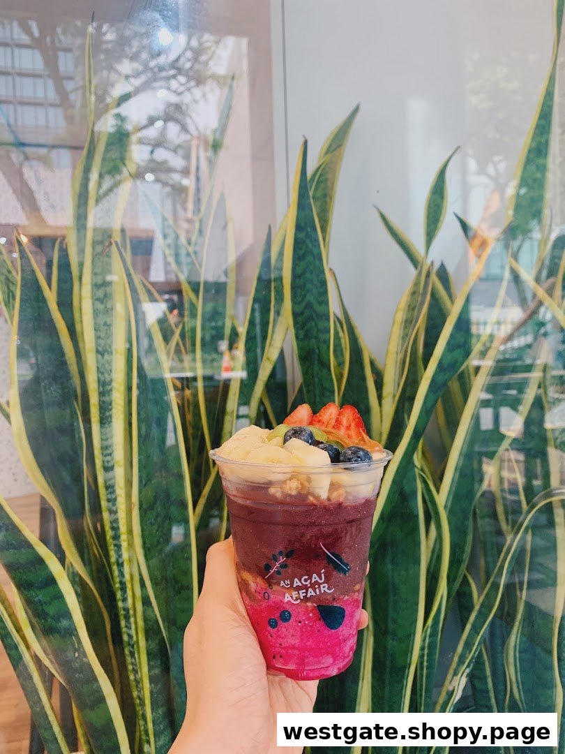 A hand holds a vibrant açaí bowl topped with fresh fruit and granola.