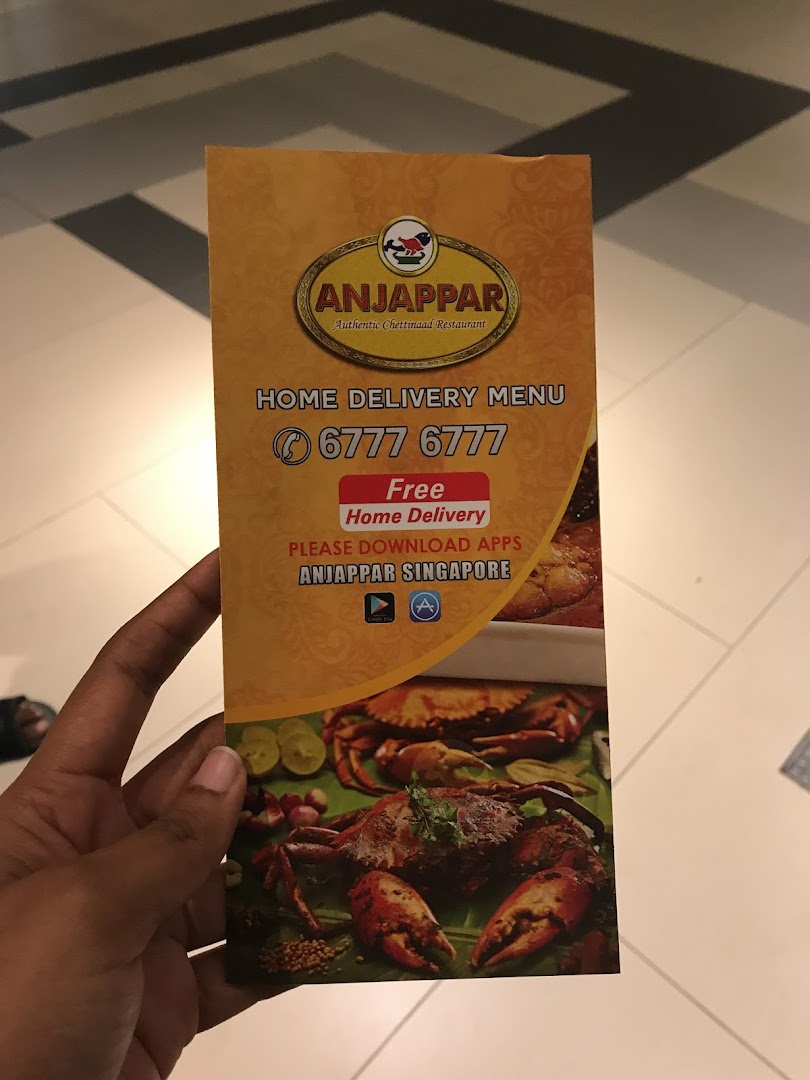 A hand holds an Anjappar Chettinaad Restaurant home delivery menu with contact details.