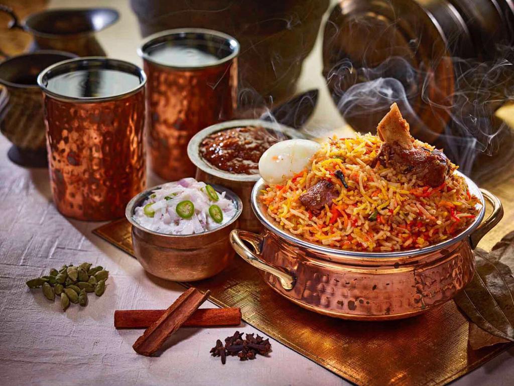 A steaming pot of flavorful biryani served with raita, gravy, and traditional spices.
