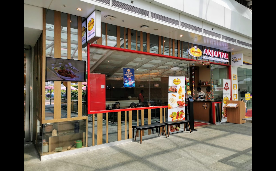 The vibrant red and wood exterior of Anjappar, an authentic Indian restaurant, within a shopping mall.