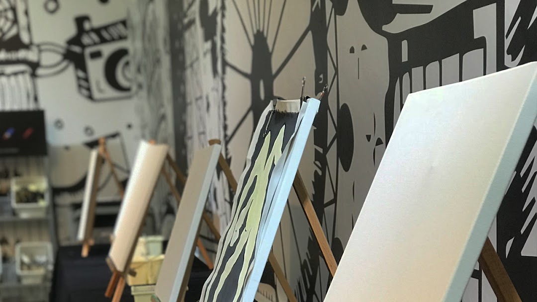 Easels with canvases set up for painting in an art studio with creative wall murals.