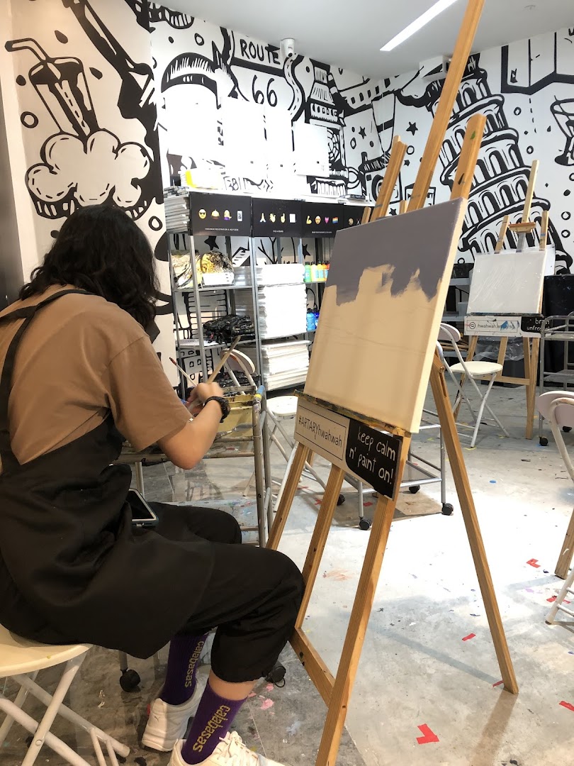 A person painting on an easel in a vibrant art studio with creative wall murals.
