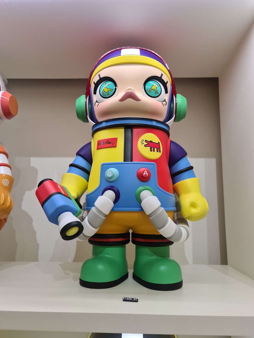 A large, colorful astronaut art toy, possibly a Keith Haring collaboration, displayed in a retail setting.
