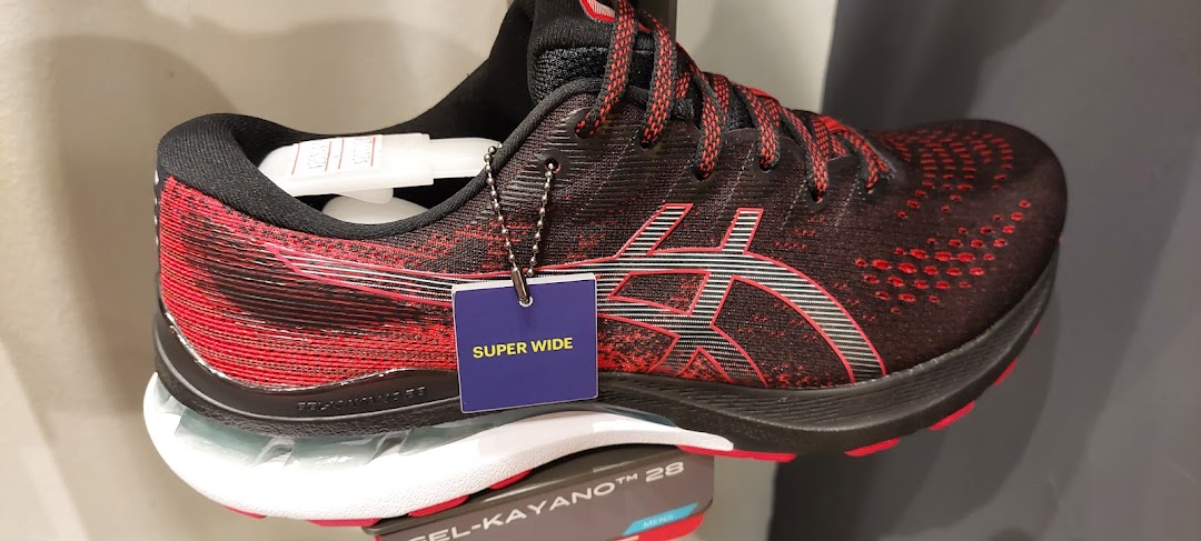 A close-up of a black and red ASICS running shoe with a 'SUPER WIDE' tag.