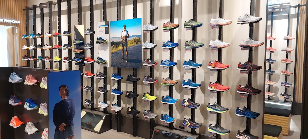 A vibrant display of ASICS athletic shoes in various colors and styles on a retail store wall.
