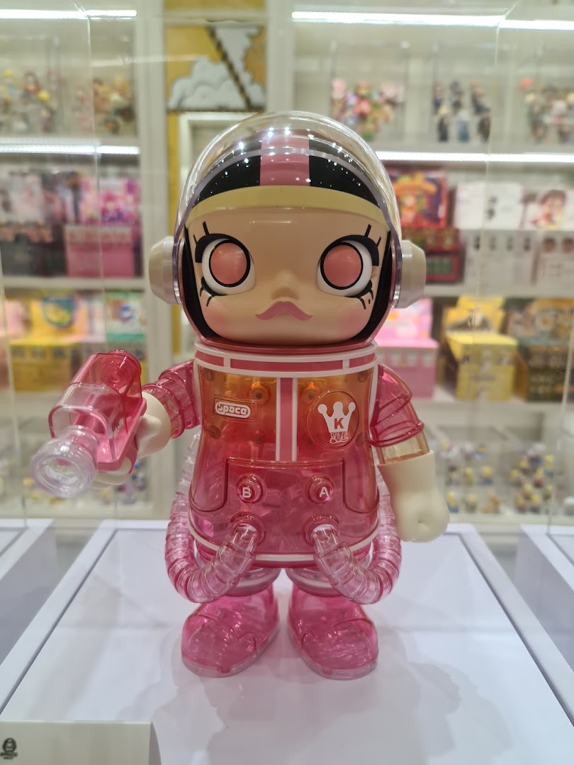 A vibrant pink and clear collectible toy figure, resembling an astronaut, displayed in a retail setting.
