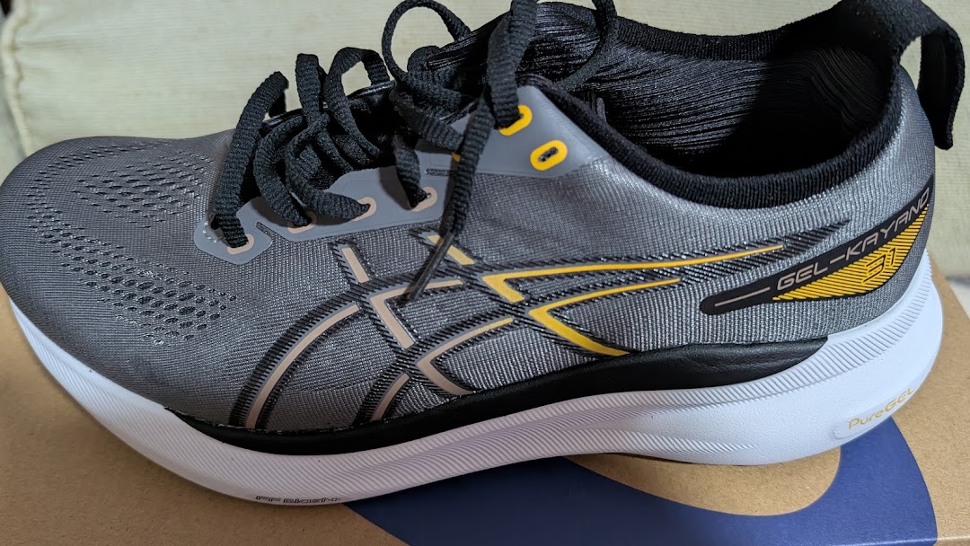 A close-up of a grey ASICS GEL-KAYANO 31 running shoe with yellow accents.
