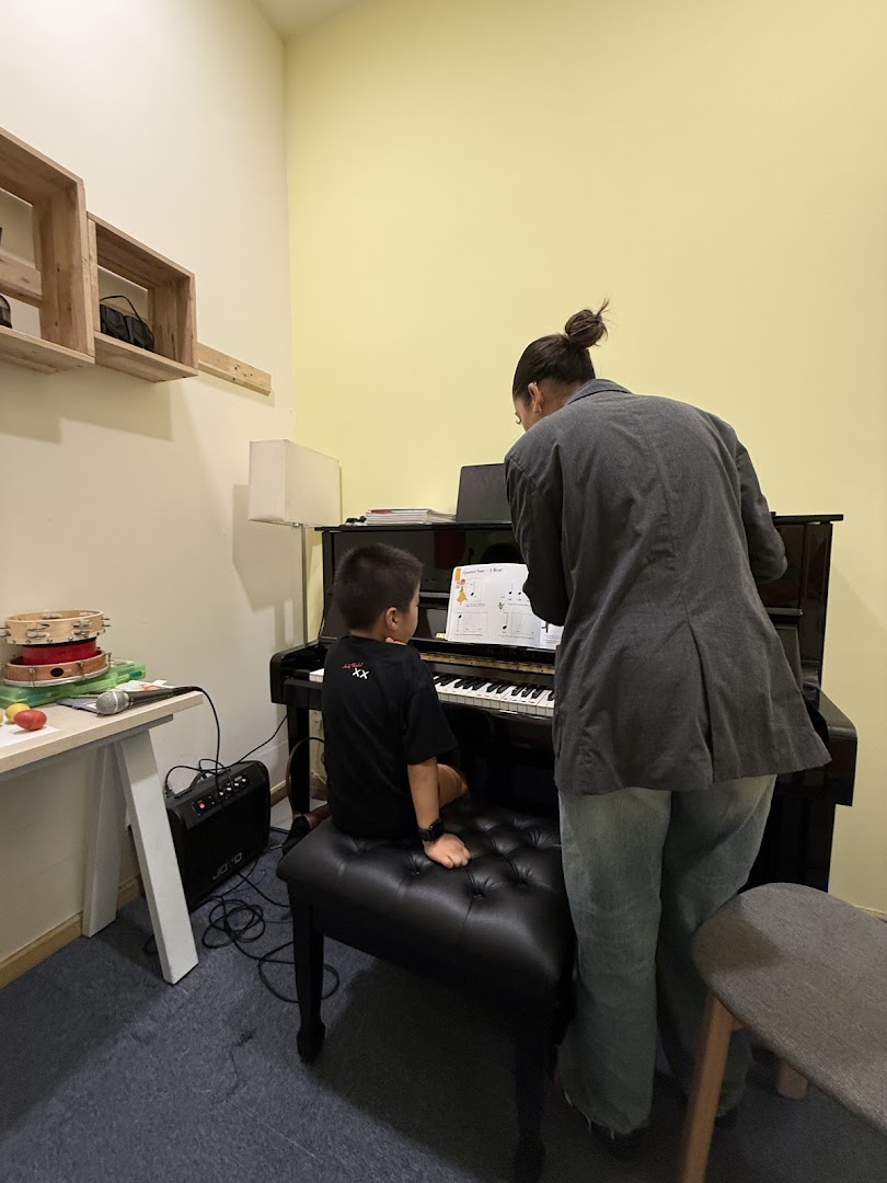 A child and an adult engaged in a piano lesson, with sheet music visible on the piano.