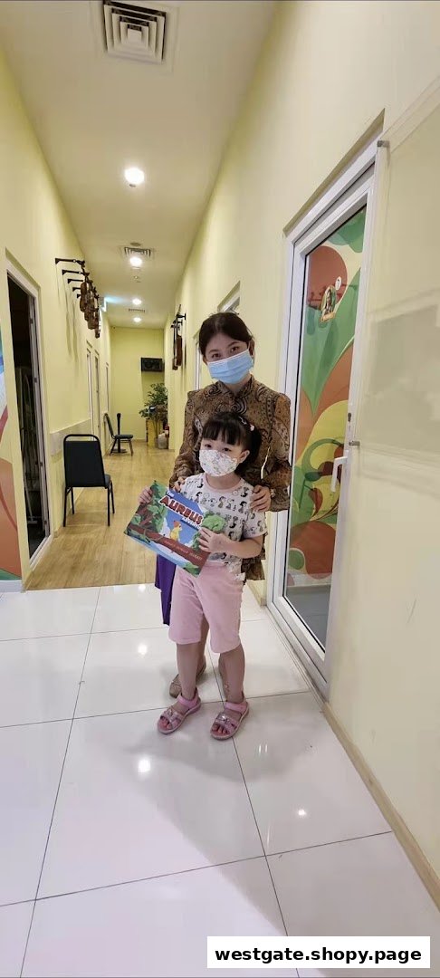A woman and a child, both masked, stand in a bright hallway, likely within Aureus Academy.