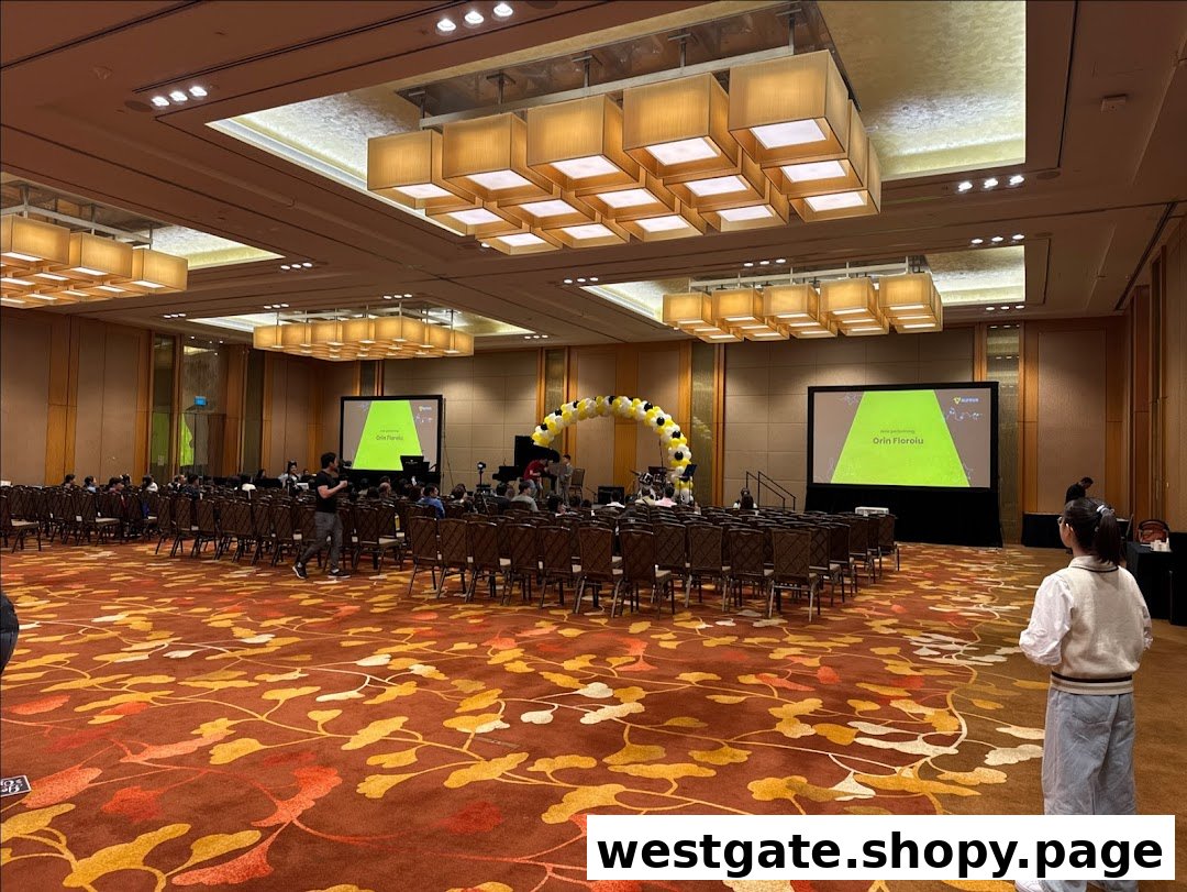 A large event hall with rows of chairs, two projection screens, and a stage, set up for a performance or presentation.