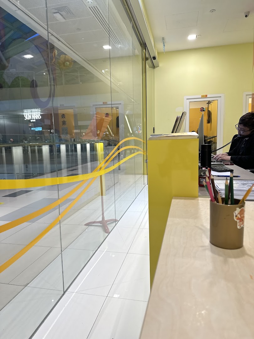 Interior view of Aureus Academy's reception area with a staff member and a view of the mall.