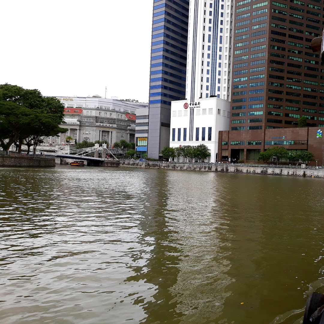 The Bank of China building stands prominently by the river, surrounded by other modern architecture and a bridge.