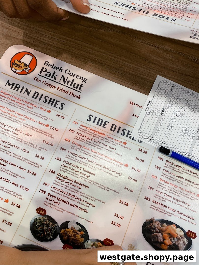 A close-up view of Bebek Goreng Pak Ndut's menu, featuring Indonesian main dishes, side dishes, soups, desserts, and drinks.