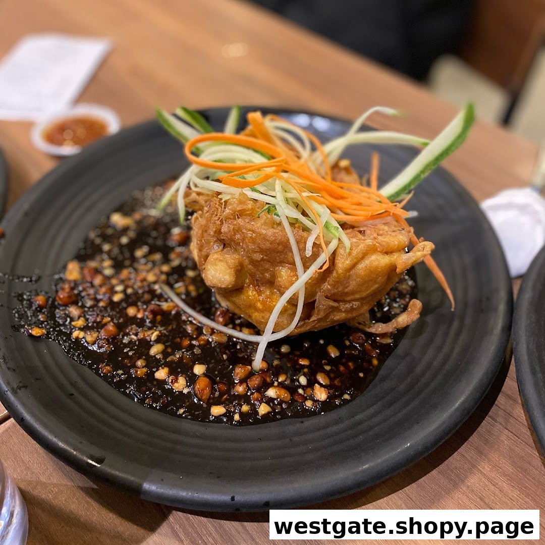A beautifully plated fried dish with dark sauce, peanuts, and fresh shredded vegetables.