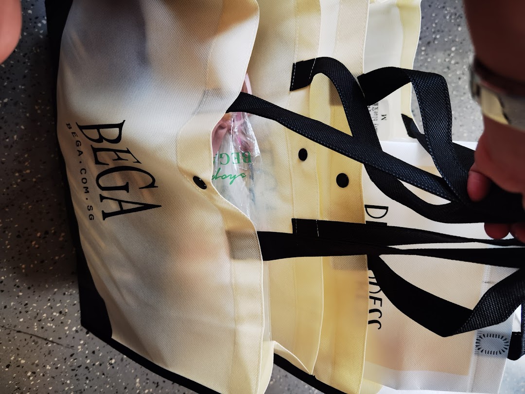 Close-up of multiple BEGA branded shopping bags with black handles and logo visible.