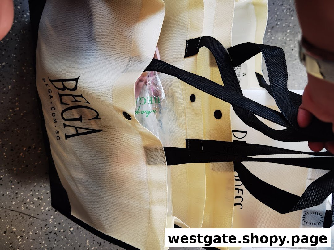 Close-up of multiple BEGA branded shopping bags with black handles and logo visible.