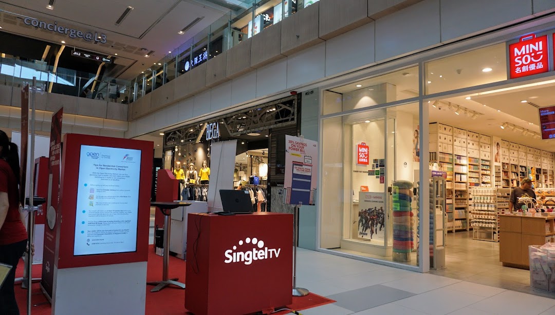 View of BEGA and MINISO shopfronts in a bustling shopping mall, with a SingtelTV booth nearby.