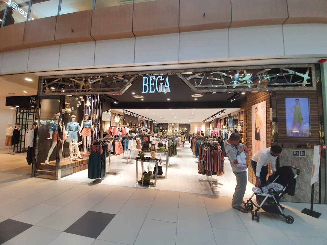 The shop front of BEGA, a fashion store, showcasing clothing on mannequins and racks, with shoppers outside.