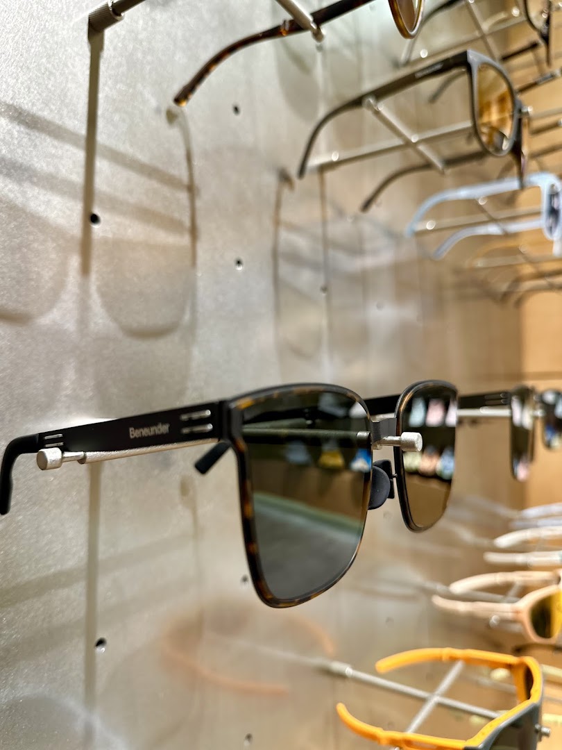 Close-up of stylish Beneunder sunglasses displayed on a wall rack.