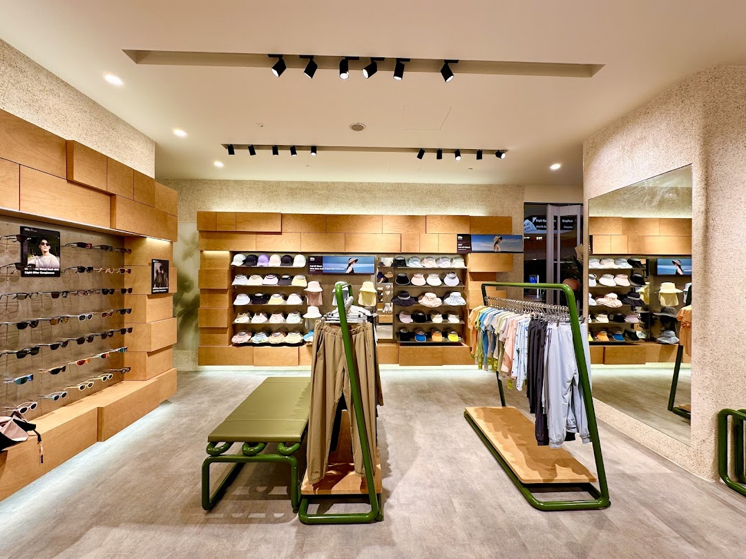 Interior of BENEUNDER shop featuring sunglasses, hats, and apparel on modern wooden and green displays.