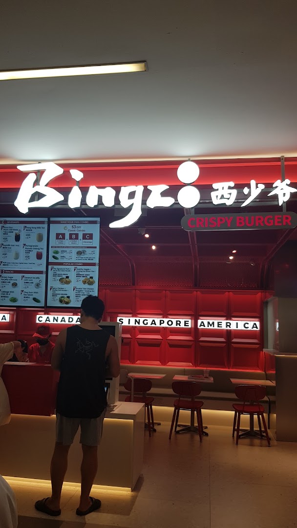 A customer orders at Bingz Singapore, featuring prominent digital menu boards with food and drink options.