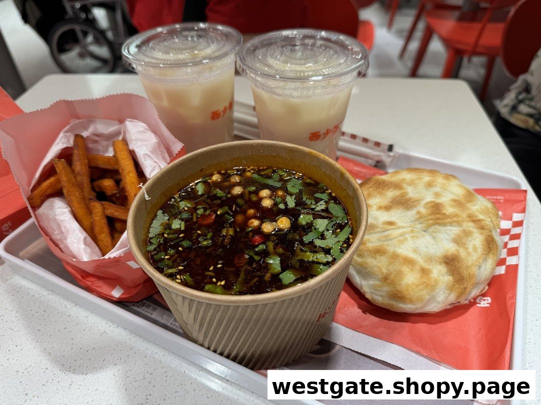 A tray featuring sweet potato fries, a spicy soup, a roujiamo bun, and two refreshing drinks.