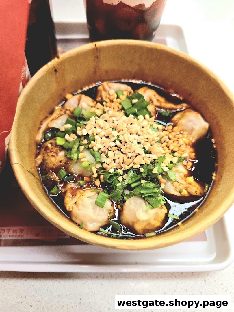 A close-up of a bowl of spicy dumplings topped with crushed peanuts and green onions.