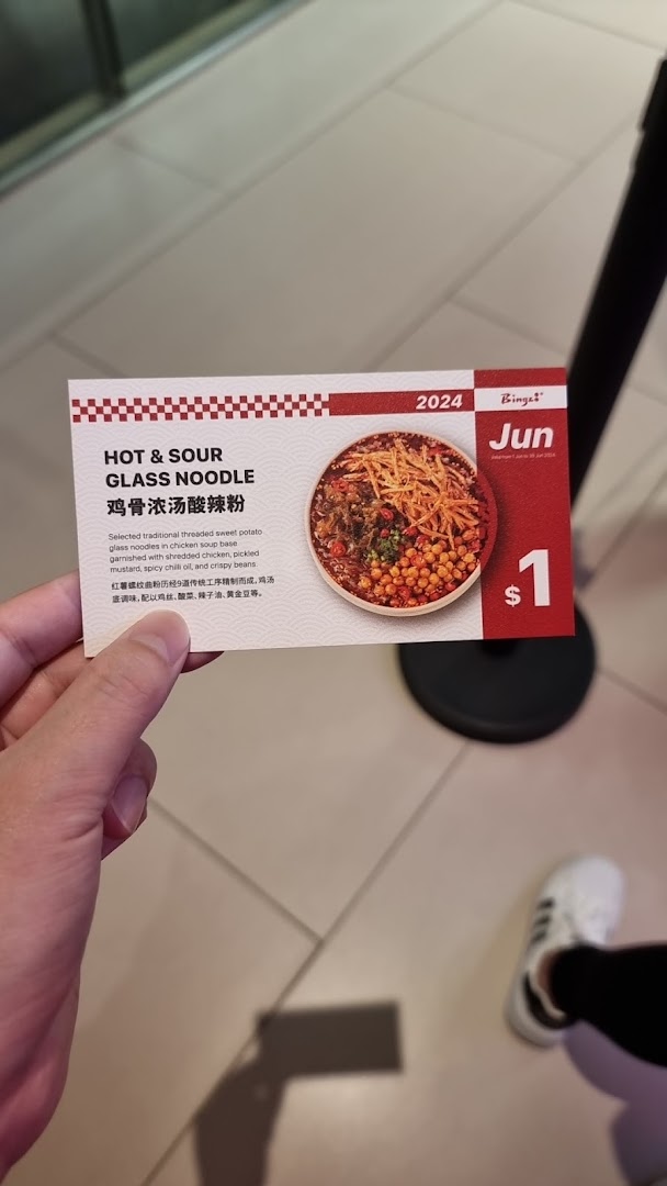 A hand holds a promotional card for Bingz's Hot & Sour Glass Noodle special.