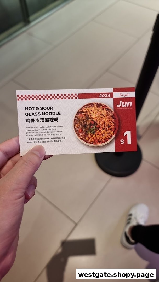 A hand holds a promotional card for Bingz's Hot & Sour Glass Noodle special.