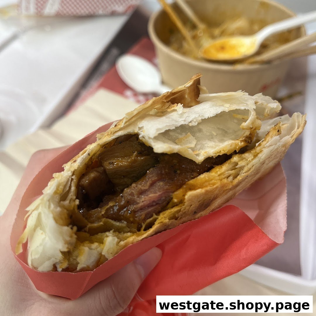 A hand holds a delicious roujiamo, showcasing its flaky pastry and savory meat filling.