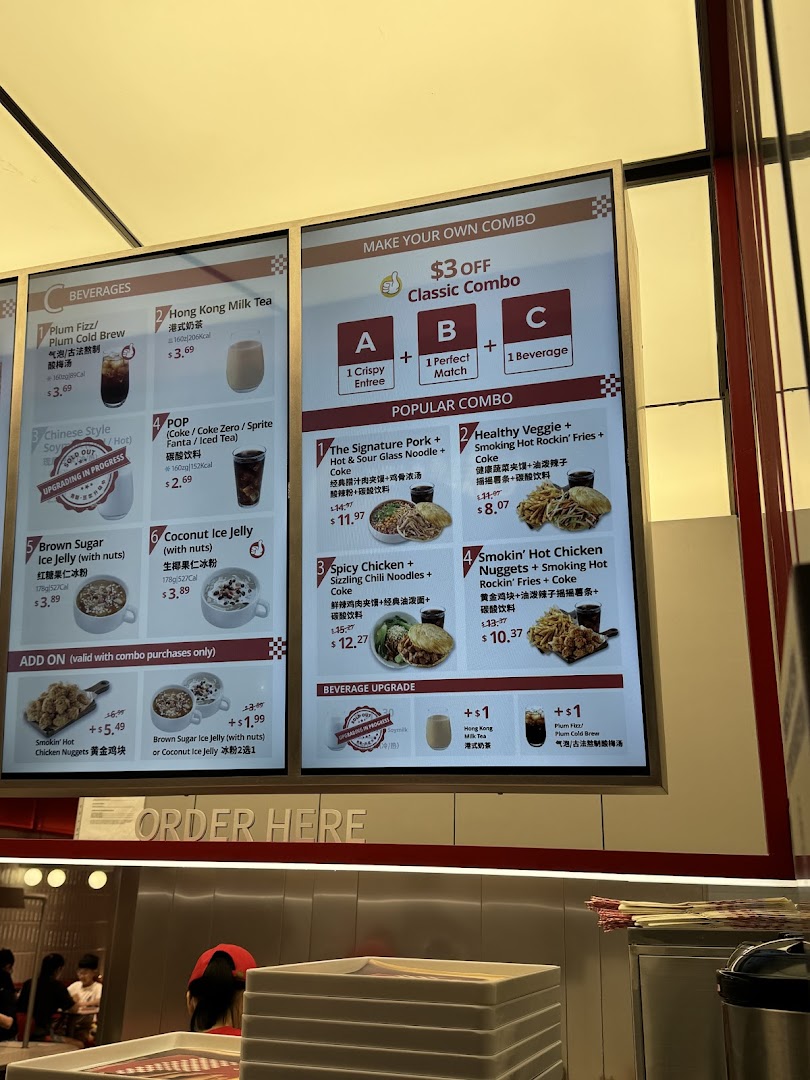 A brightly lit digital menu board displaying various food and beverage options, combos, and add-ons.