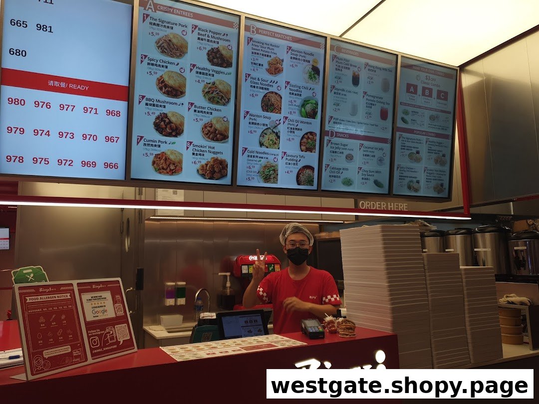 A staff member stands behind the counter with digital menu boards displaying various food and drink options.