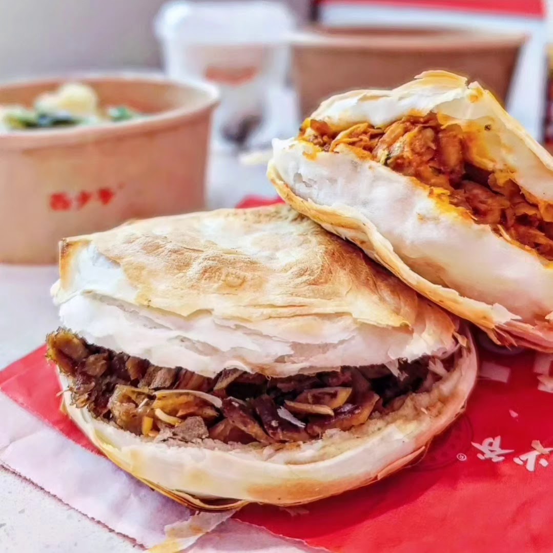 Two delicious Bingz roujiamo, one with meat and another filling, served on a red paper.