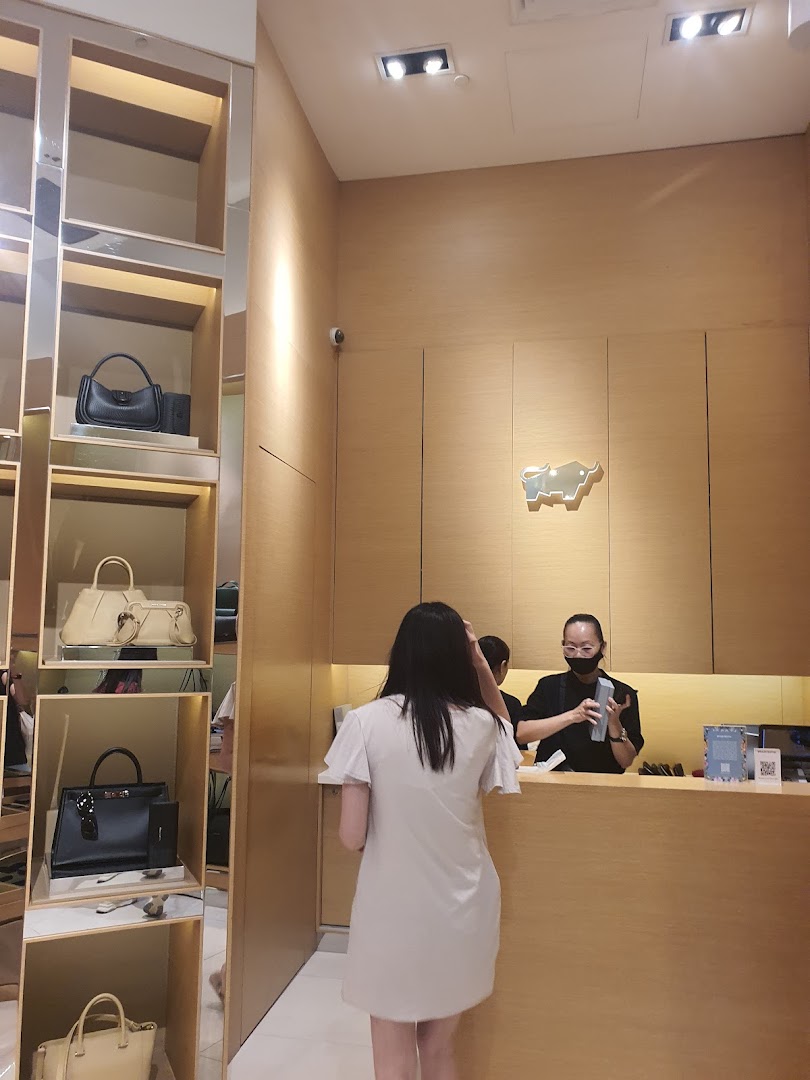 A customer interacts with staff at the counter of a Braun Büffel store, showcasing luxury handbags.