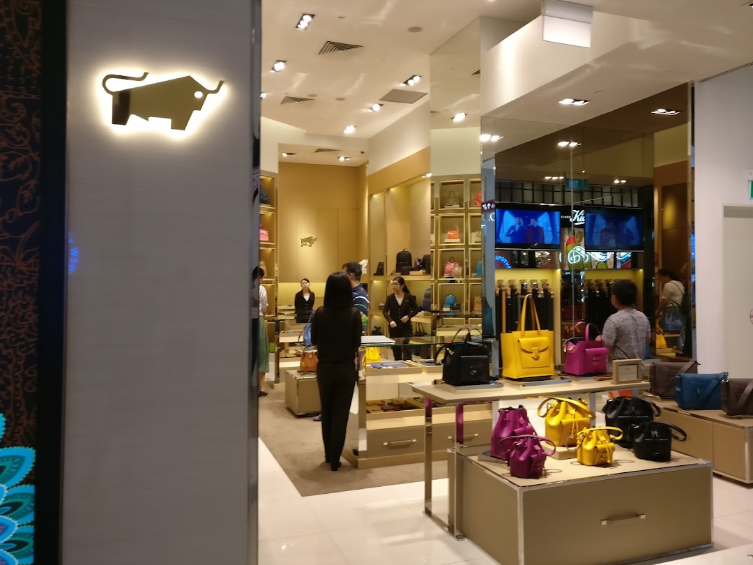 Interior view of Braun Büffel store showcasing colorful leather handbags and accessories with customers browsing.