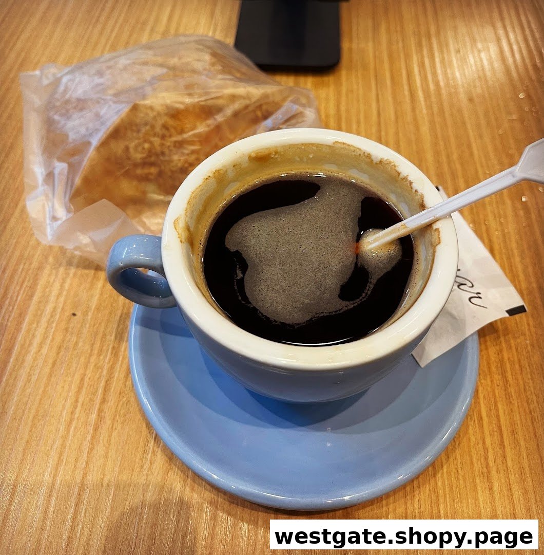 A cup of black coffee and a pastry on a wooden table, ready for a delightful break.