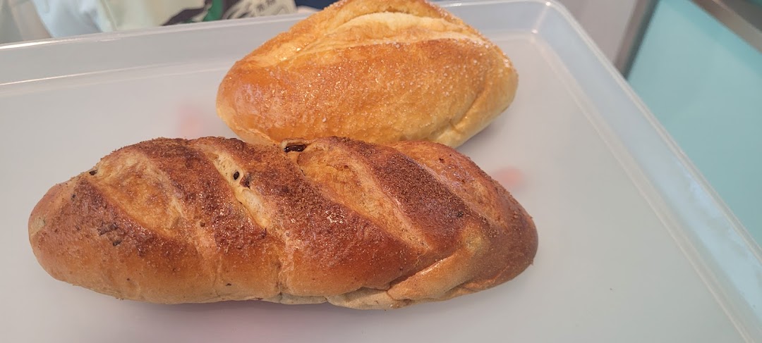 Two freshly baked loaves of bread, one plain and one with raisins, on a white tray.